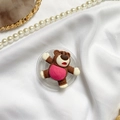 Nahaufnahme Lotso Bär Cartoon Handyhalterung auf elegantem weißem Satin-Hintergrund - Farbkontrast Bär / Braun