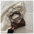 Détail d'un sac en cuir café foncé avec design plissé et bandoulière dorée - Marron
