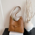 Minimalist brown leather shoulder bag with gold buckle on a stylish book display - Brown