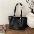 Bolso tote negro vintage con remaches plateados y correa ajustable en superficie de madera - Negro