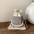 Luxe marble texture bucket bag with pearl handle and gold chain strap on vintage book - Khaki