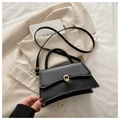 Detalle de un bolso bandolera negro con hebilla dorada sobre un elegante blazer beige - Negro