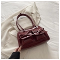 Dettaglio di una borsa bowling bordeaux in finta pelle lucida con fiocchi decorativi - Rosso
