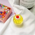 Detailaufnahme von gelbem Gelee-Kuchen-Handygriff mit roter Kirsche und weißem Sahnehäubchen - Cremige Kirsche-Gelb