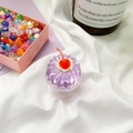 Makroaufnahme von lila Gelee-Cupcake Handyhalter mit roter Kirsche auf Stoff - Cremige Kirsche-Lila