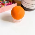 Macrodetail van zachte oranje bolvormige make-upspons op een heldere standaard - Oranje