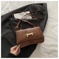 Close-up of caramel brown PU leather shoulder bag with golden H-shaped buckle and fine stitching - Brown