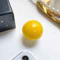 Glossy bright yellow spherical expanding phone grip with transparent base on a desk - Yellow