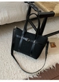 Détail du cabas en maille noire avec boucle argentée sur un tapis blanc doux et élégant - Noir