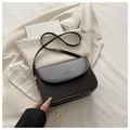 Close-up van donkere leren crossbodytas met Fashion Bags reliëf op beige blazer - Zwart
