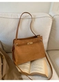 Nahaufnahme einer braunen Wildledertasche mit goldenem Drehverschluss und schlichtem Riemen - Braun