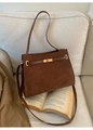 Detail der dunkelbraunen Wildleder-Tragetasche mit goldenem Drehverschluss auf Beige - Kaffeebraun