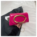 Detail of a magenta patent leather bag featuring a large gold oval buckle and chain - Rose Red