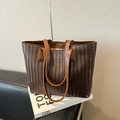 Bolso tote de cuero trenzado marrón oscuro con correa marrón claro sobre el sofá - Con Colgante / Marrón
