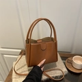 Bolso cubo vintage marrón con neceser interior y bandolera en un fondo acogedor - Marrón