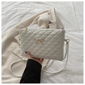 Detail shot of white quilted shoulder bag with gold bow ornament and metal zipper closure - White