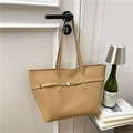 Bolso tote beige minimalista con cierre dorado y correas finas en un fondo artístico - Caqui