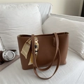 Sac cabas en cuir marron minimaliste avec foulard en soie sur fond de canapé blanc - Fauve