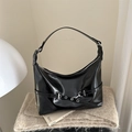 Borsa hobo nera lucida con fibbie argentate e dettagli su uno sfondo interno minimalista - Nero