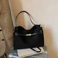Large black matte tote bag with silver buckle and suede texture on a suitcase - Black