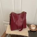 Vintage burgundy leather hobo bucket bag with side pockets on a cozy table setting - Red