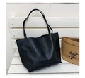 Detalle de un bolso tote negro de gran capacidad en cuero PU sobre un banco blanco - Negro