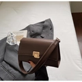 Detalle del bolso de cuero sintético café con hebilla dorada y correa de hombro ancha - café