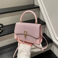 Sac à main rose avec strass et boucle dorée en U sur un support d'exposition moderne - Rose