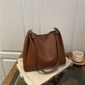 Bolso tote vintage de cuero marrón con correas anudadas sobre un fondo minimalista - café
