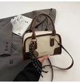Detail view of retro bowling-style handbag on gray suit with decorative rope charm - With Pendant / White & Coffee