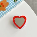 Detail of red heart phone grip with built-in mirror and retractable base on desk - Red