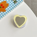 Detail of a light yellow heart-shaped mirror phone socket on a white surface - Yellow
