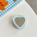 Macro detail of heart-shaped mirror phone grip with light blue translucent outer edge - Blue