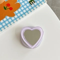 Detail view of heart-shaped phone grip featuring lavender frame and integrated mini mirror - Purple