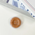 Macro view of caramel button phone grip with speckled texture and transparent base - Orange