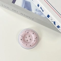 Detail shot of a pink button phone grip with marble ink pattern on a white desk background - Pink