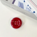 Macro view of a red button-shaped phone airbag stand with glossy finish and four holes - Red