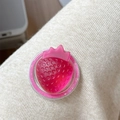 Close-up of a 3D translucent red strawberry phone grip on white knitted fabric - Iridescent Strawberry-Rose Red
