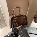 Retro brown Boston bag with contrast handles and adjustable strap in domestic setting - Coffee With Pendant