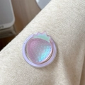 Macro shot of 3D holographic strawberry phone grip with glittery purple base on fabric - Iridescent Strawberry-Purple