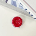 Detail of red ink-splatter button phone grip with four holes and a clear base - Rose Red