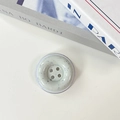 Detail of the minimalist button-shaped phone grip with blue ink speckle pattern - Off-white