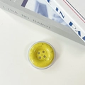 Top view of yellow button phone grip with black ink splatter pattern and 4 decorative holes - Dark Yellow