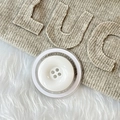 Vue macro du bouton blanc à 4 trous sur support magnétique et tissu tricoté kaki - Blanc