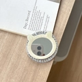 Detalle del soporte para móvil con orejas de gato, pedrería y espejo sobre madera clara - Espejo de Gato con Textura de Concha / Blanco Roto