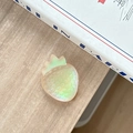 Iridescent strawberry phone grip with holographic effect on a wooden table setup - Iridescent Orange