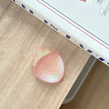 Macro view of a 3D pink strawberry phone grip with iridescent finish on wooden surface - Iridescent Red