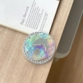 Macro view of holographic dolphin phone grip with rhinestones on a wooden surface - Rendered Block Dolphin Mirror / Purple & Green