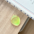 Detail shot of a gradient strawberry phone grip with textured seeds on a desk setting - Iridescent Yellow