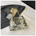 Dettaglio delle paillettes oro, argento e nere su una borsa a tracolla di tendenza - Oro
